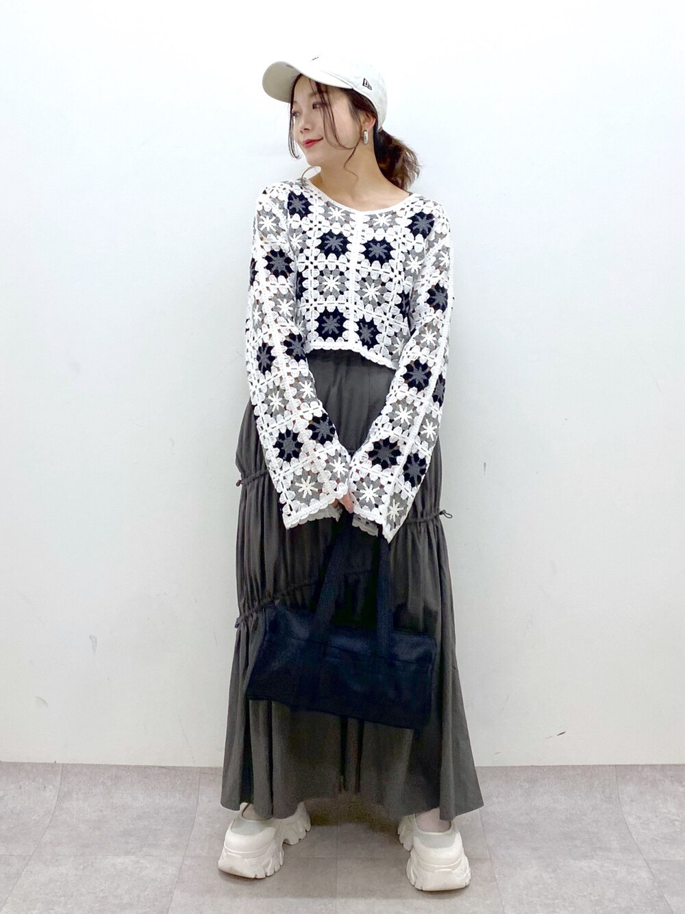 グレー系のスカート、ホワイト系のカーディガン/ボレロ、ブラック系のドラムバッグを着用したレディースの春コーディネートの9枚目の写真