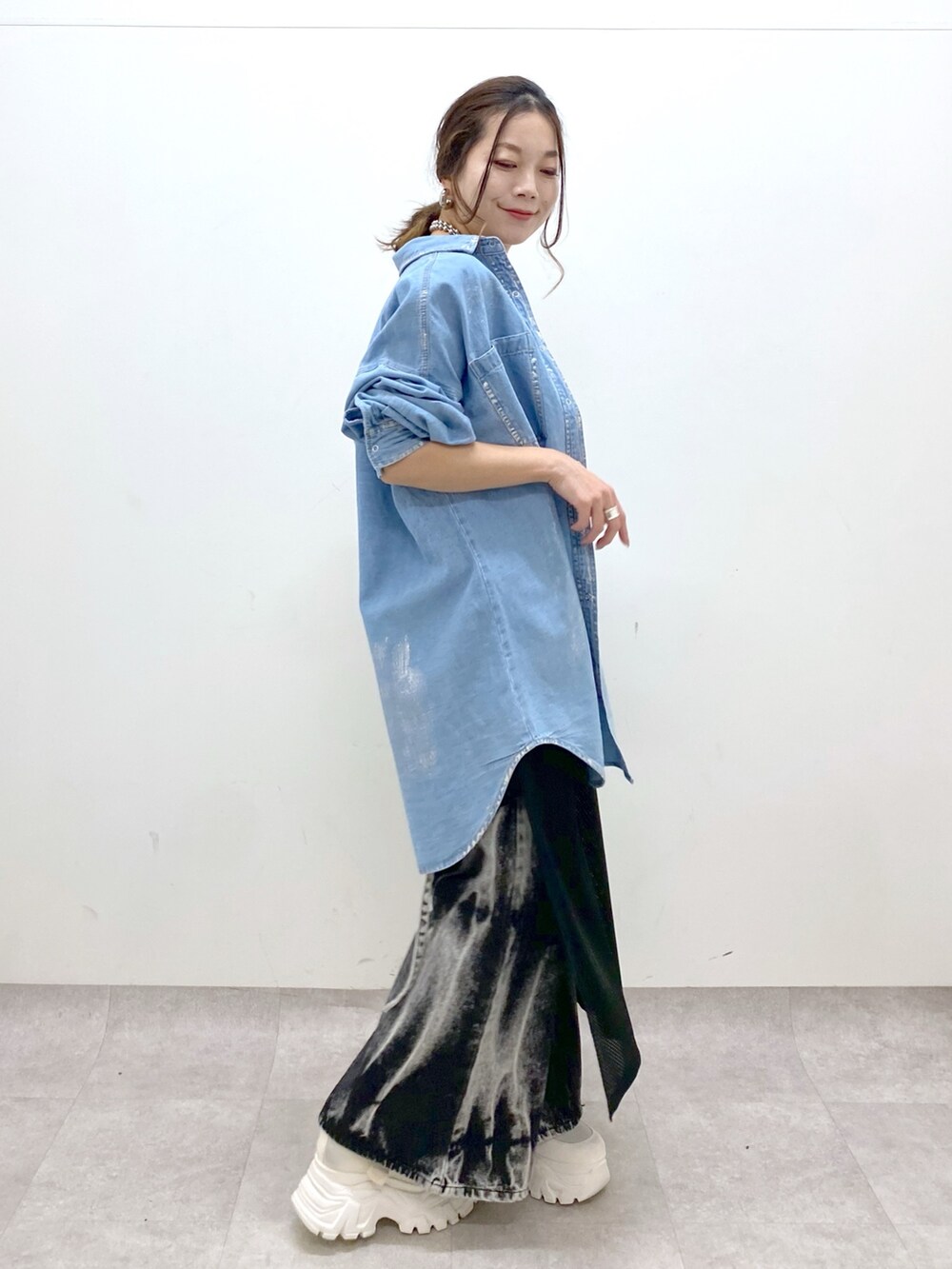 ブラック系のデニムパンツ、ホワイト系のスニーカー、ブラック系のワンピースを着用したレディースの春コーディネートの5枚目の写真