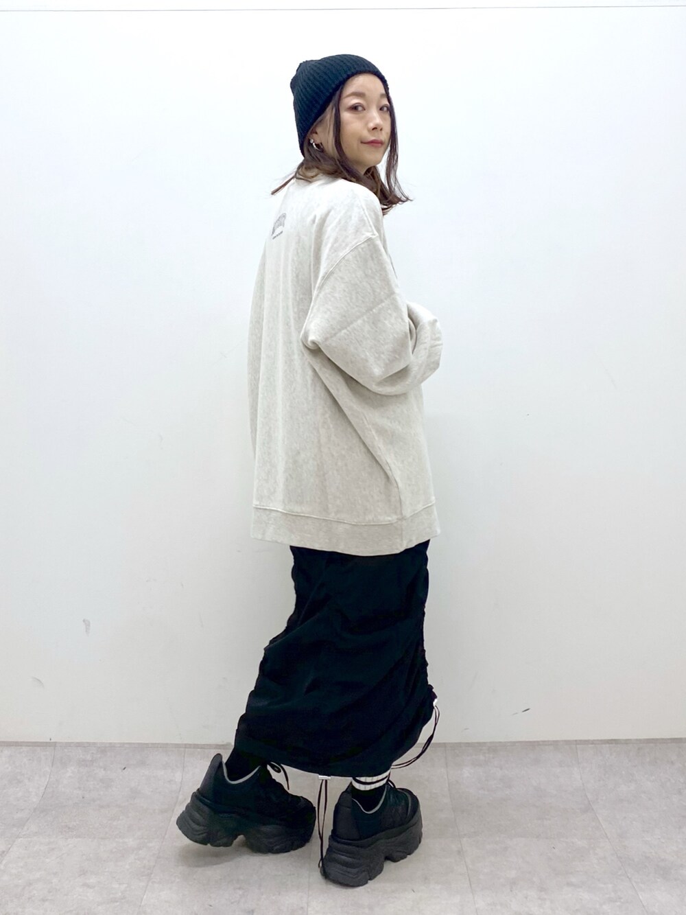 ベージュ系のスウェット、ブラック系のワンピース、ブラック系のスニーカーを着用したレディースの冬コーディネートの8枚目の写真