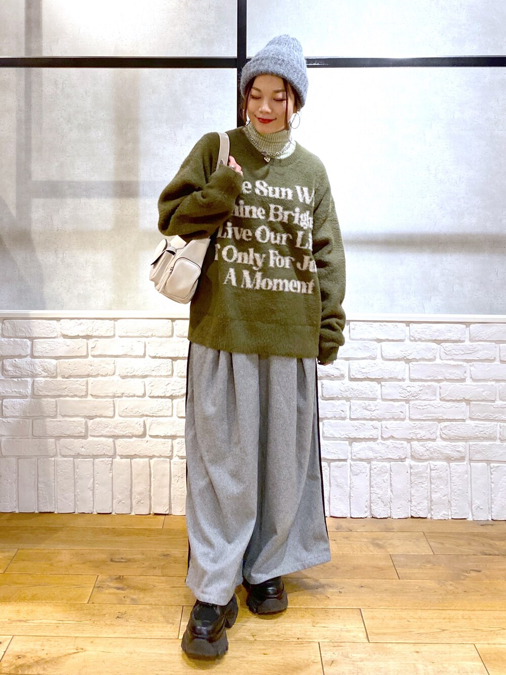 ブラック系のスラックス、グリーン系のTシャツ/カットソー、ブラック系のブーツを着用したレディースの冬コーディネートの9枚目の写真