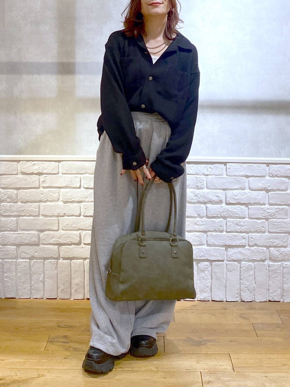ブラック系のスニーカー、グリーン系のボストンバッグ、グレー系のスウェットパンツを着用したレディースの秋コーディネートの3枚目の写真