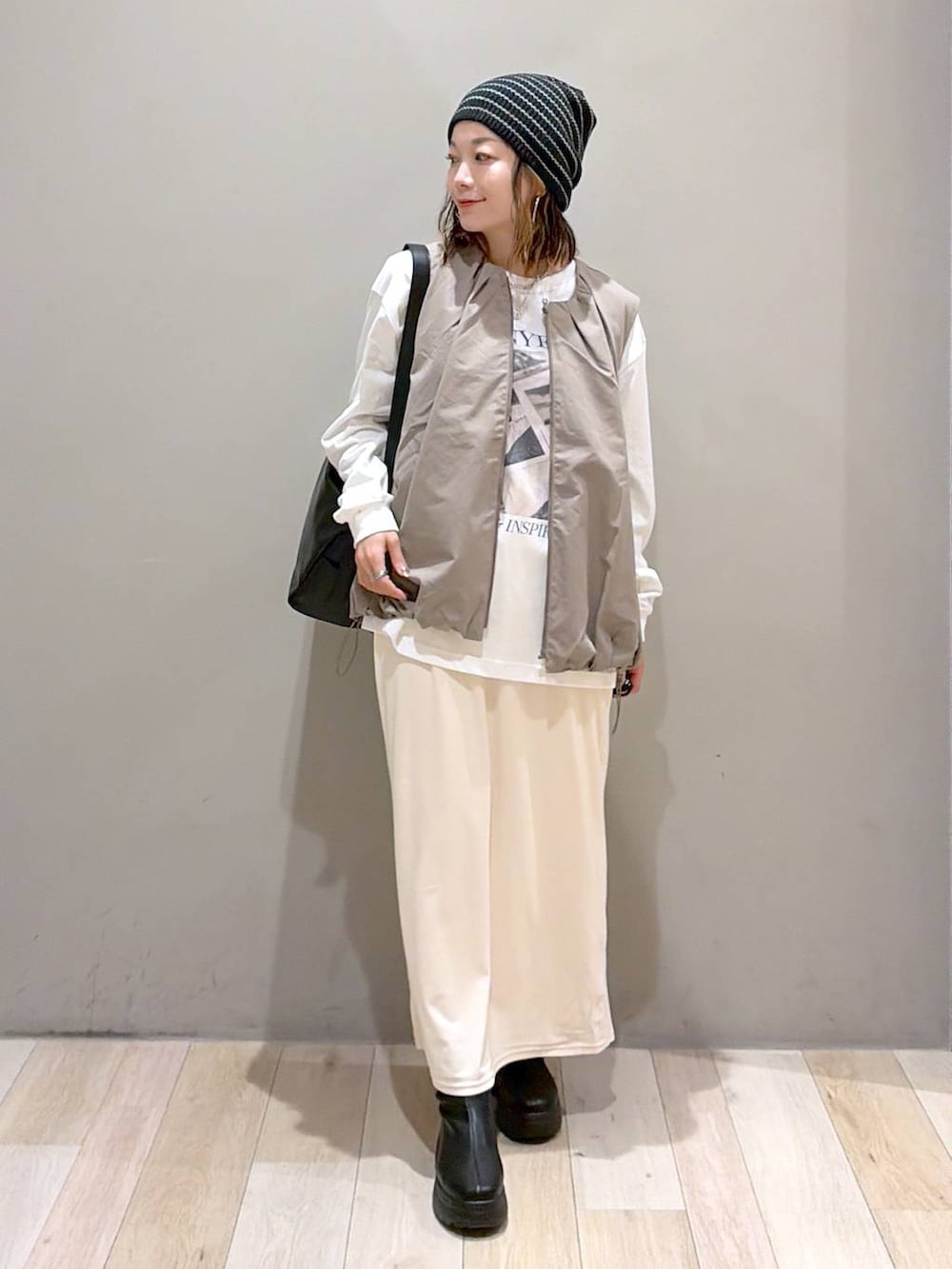 グレー系のベスト、ブラック系のブーツ、ホワイト系のTシャツ/カットソーを着用したレディースの秋コーディネートの8枚目の写真