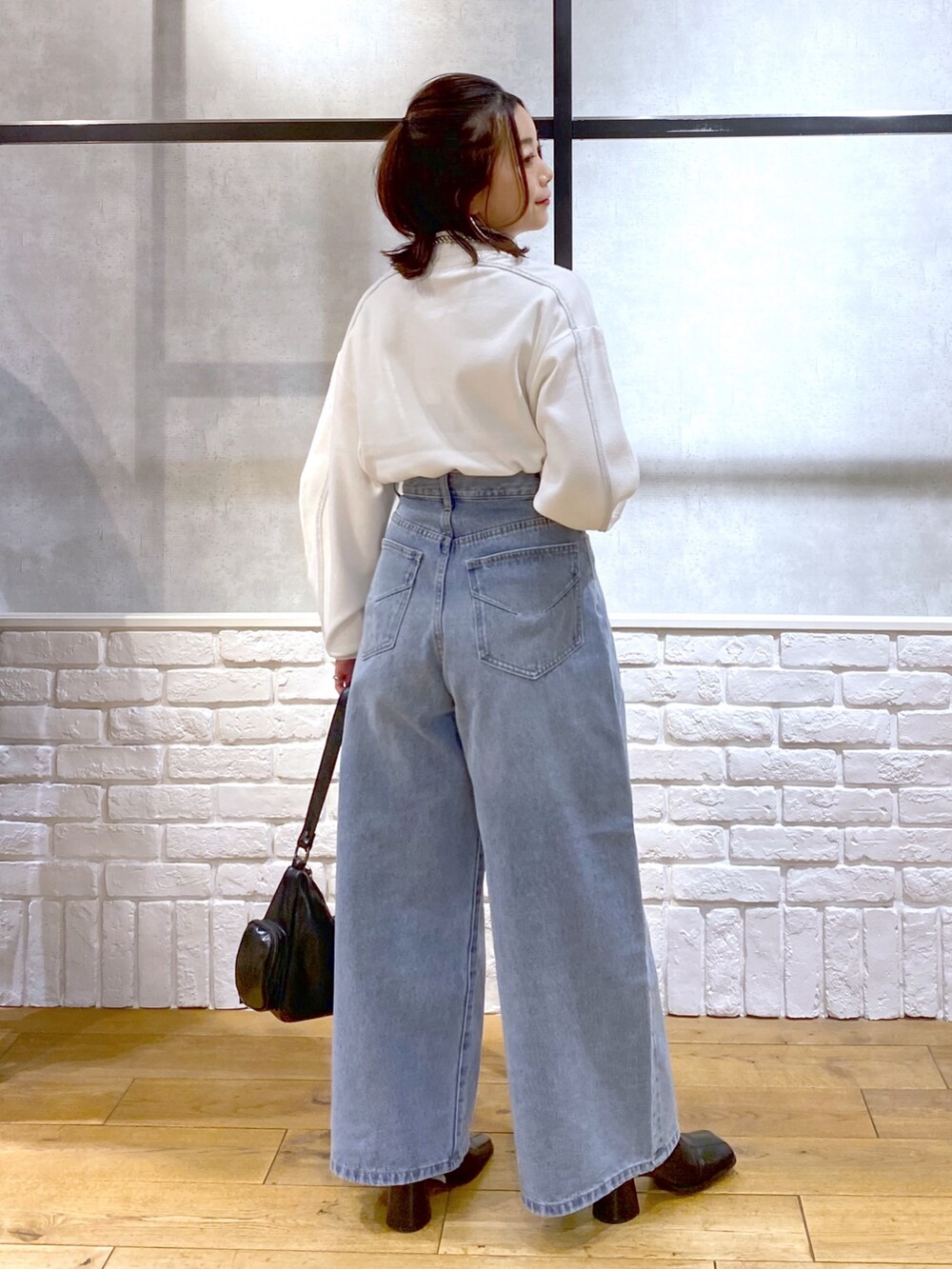 ホワイト系のニット/セーター、ブルー系のデニムパンツ、ブラック系のショルダーバッグを着用したレディースの冬コーディネートの7枚目の写真