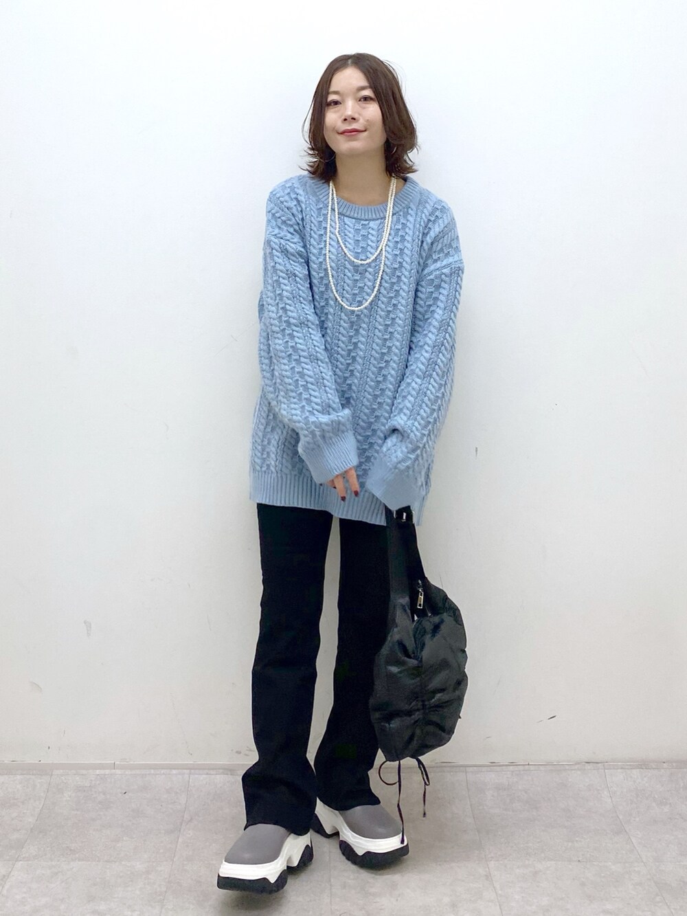 グリーン系のニット/セーター、ブラック系のショルダーバッグ、ブラック系のデニムパンツを着用したレディースの冬コーディネートの7枚目の写真