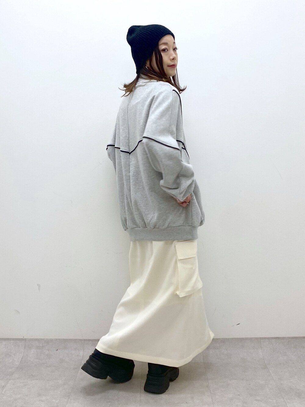 ホワイト系のスカート、ブラック系のスニーカー、グレー系のスウェットを着用したレディースの冬コーディネートの5枚目の写真