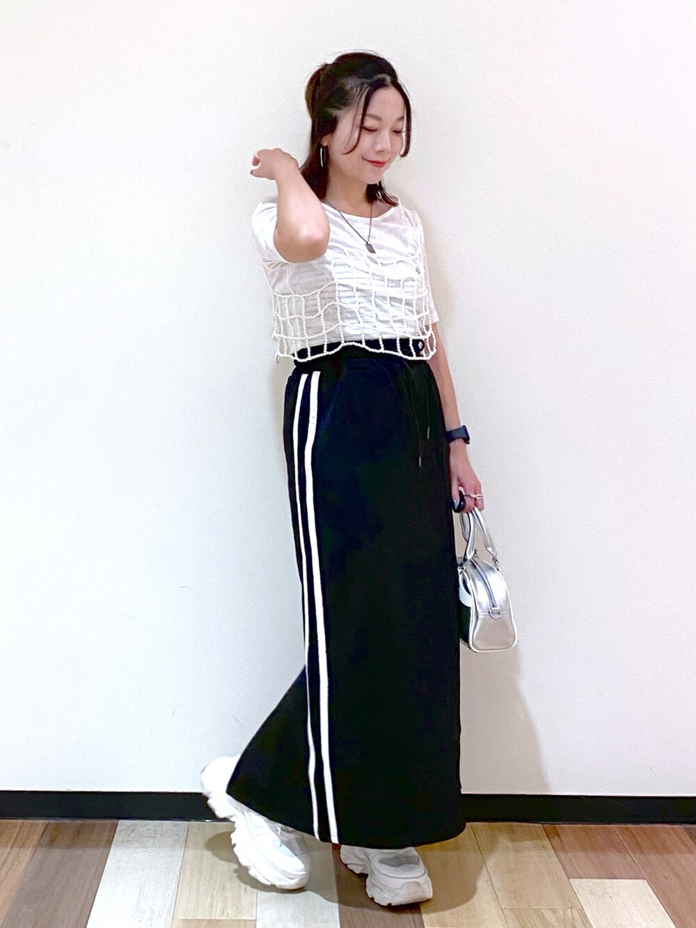ブラック系のスカート、シルバー系のショルダーバッグ、ホワイト系のスニーカーを着用したレディースの夏コーディネートの5枚目の写真