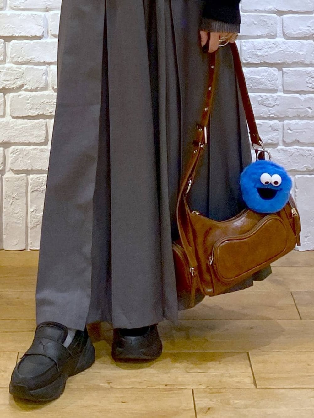 ブラック系のローファー、グレー系のスカート、ブラウン系のショルダーバッグを着用したレディースの冬コーディネートの4枚目の写真