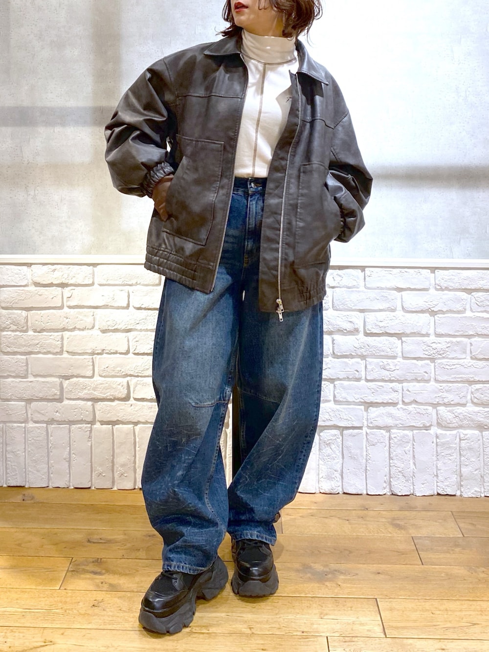 グレー系のブルゾン、ブルー系のデニムパンツ、ブラック系のブーツを着用したレディースの冬コーディネートの3枚目の写真