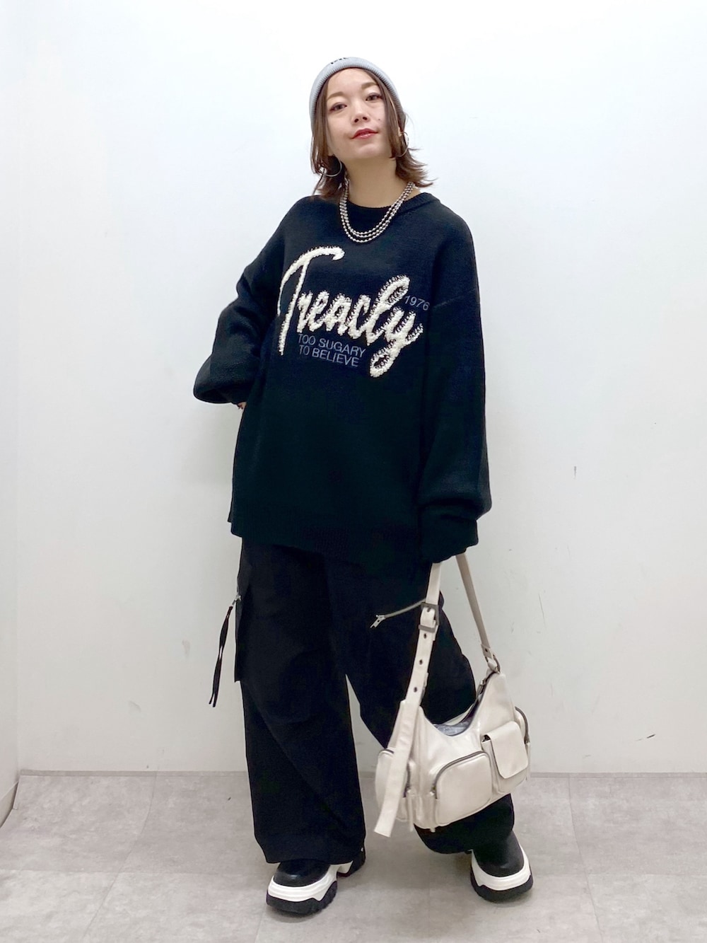 ブラック系のニット/セーター、ブラック系のカーゴパンツ、ホワイト系のショルダーバッグを着用したレディースの冬コーディネートの9枚目の写真