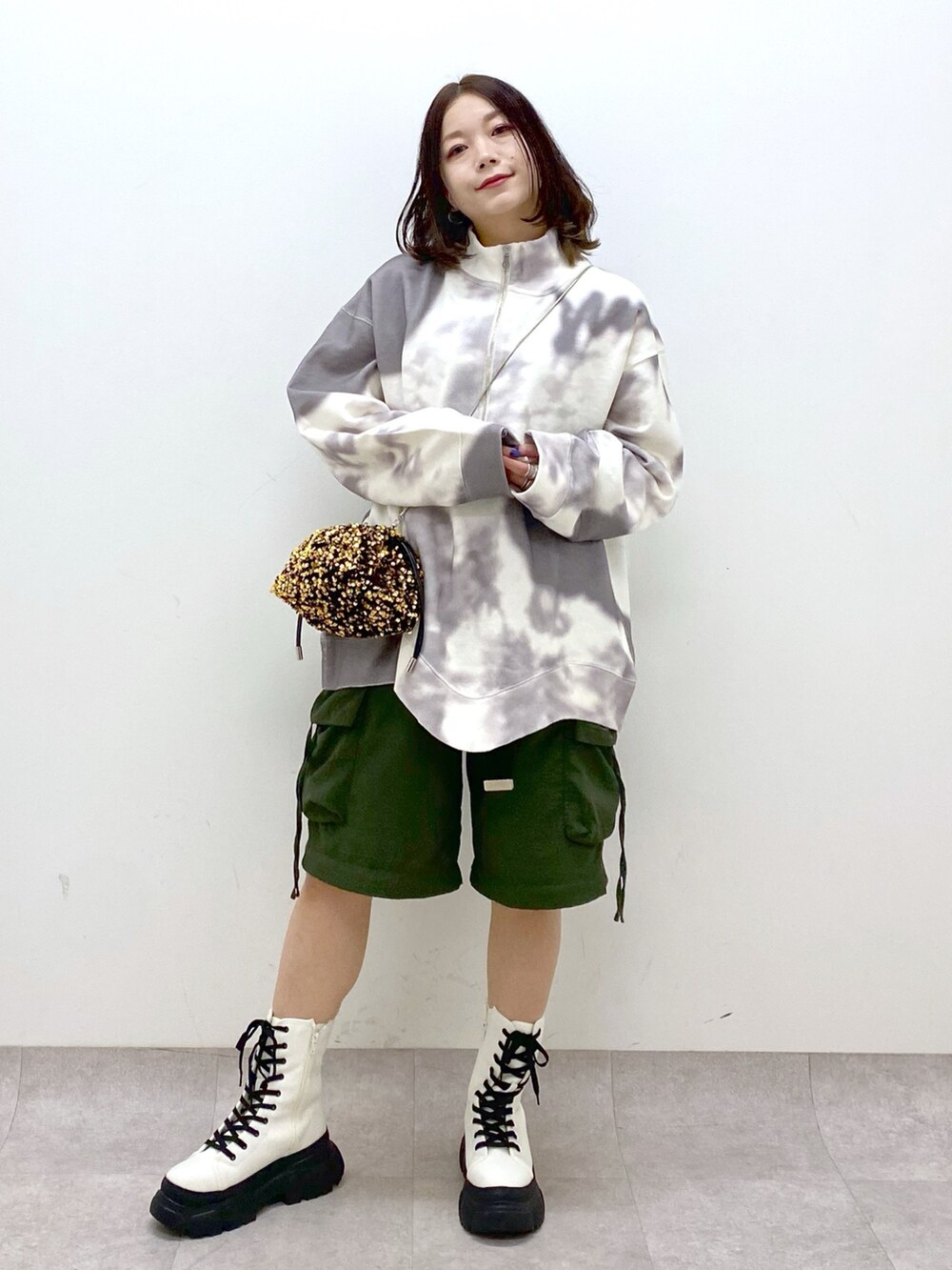 グリーン系のカーゴパンツ、ホワイト系のブーツ、ゴールド系のショルダーバッグを着用したレディースの冬コーディネートの9枚目の写真