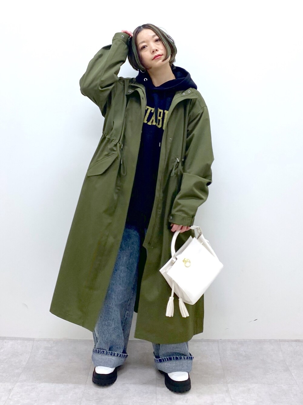 グリーン系のモッズコート、ブラック系のトップス、ブルー系のデニムパンツを着用したレディースの冬コーディネートの2枚目の写真