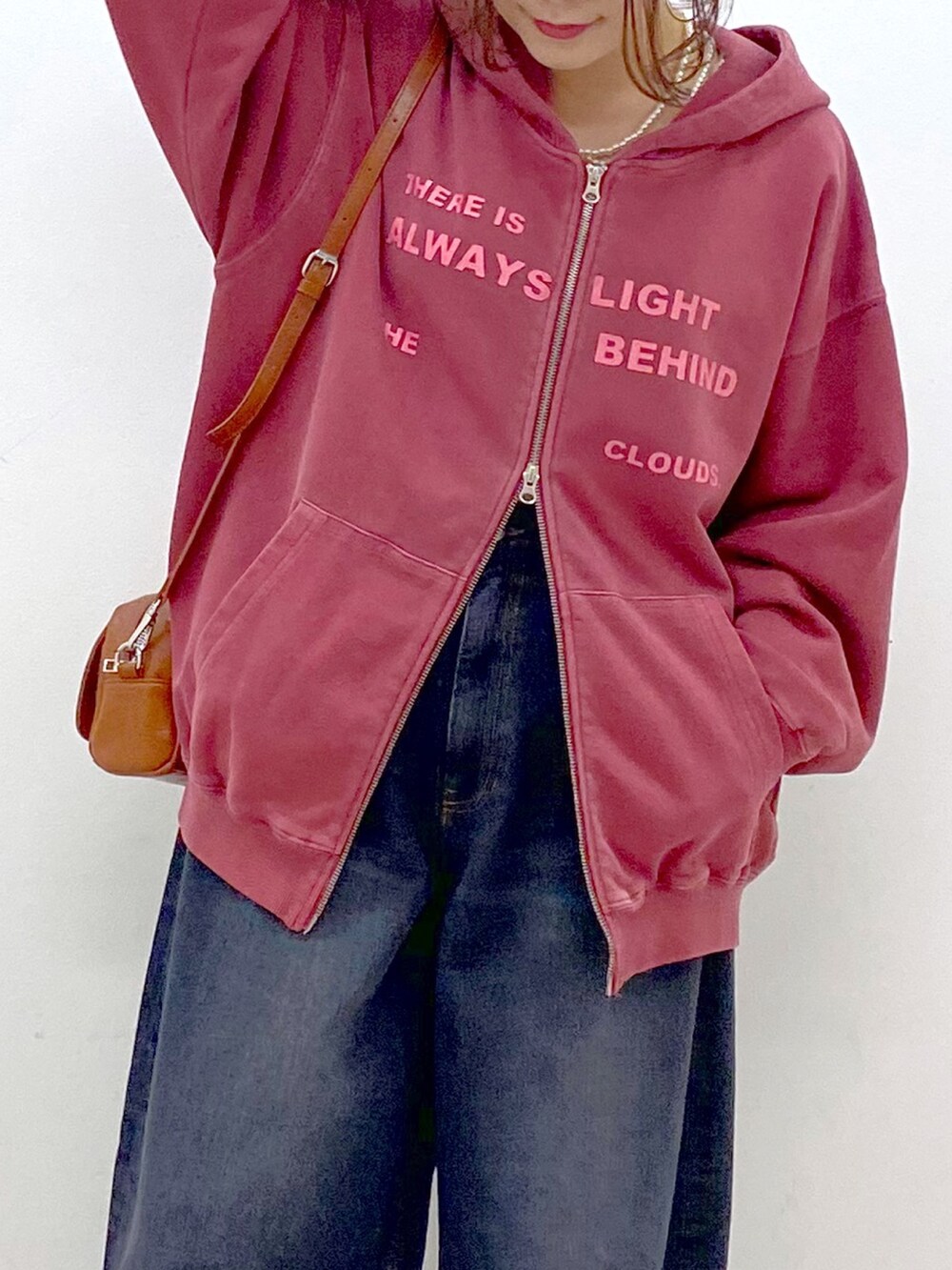 レッド系のスウェット、ブラック系のデニムパンツ、ブラック系のローファーを着用したレディースの冬コーディネートの2枚目の写真