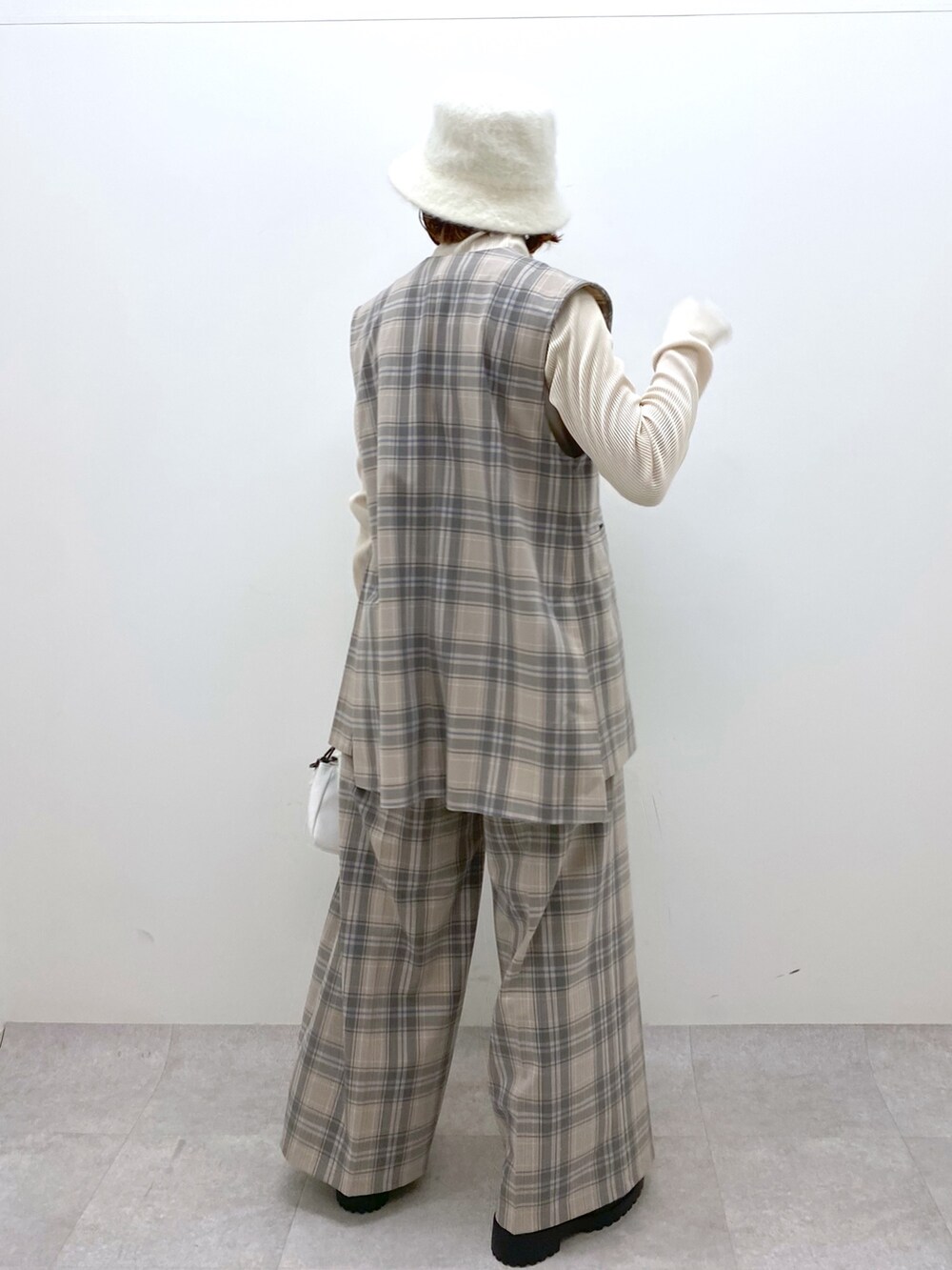 ホワイト系のバッグ、ブラック系のシューズ、グレー系のパンツを着用したレディースの秋コーディネートの4枚目の写真