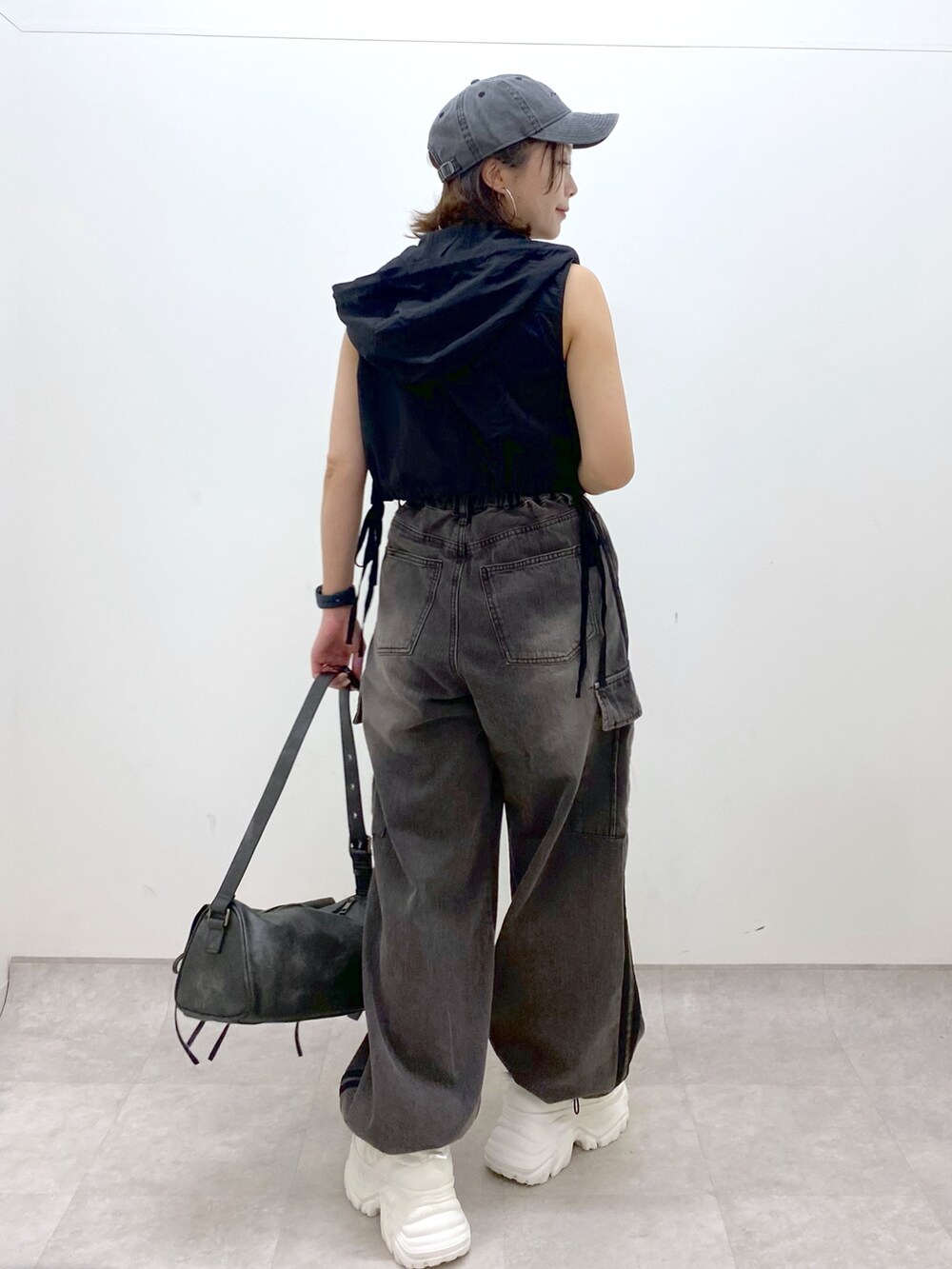 ブラウン系のデニムパンツ、ブラック系のショルダーバッグ、ホワイト系のスニーカーを着用したレディースの夏コーディネートの6枚目の写真