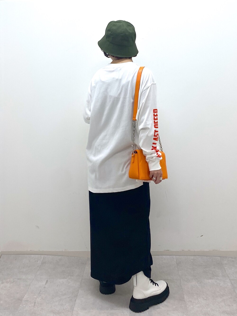 ブラック系のスカート、ホワイト系のブーツ、オレンジ系のショルダーバッグを着用したレディースの秋コーディネートの4枚目の写真