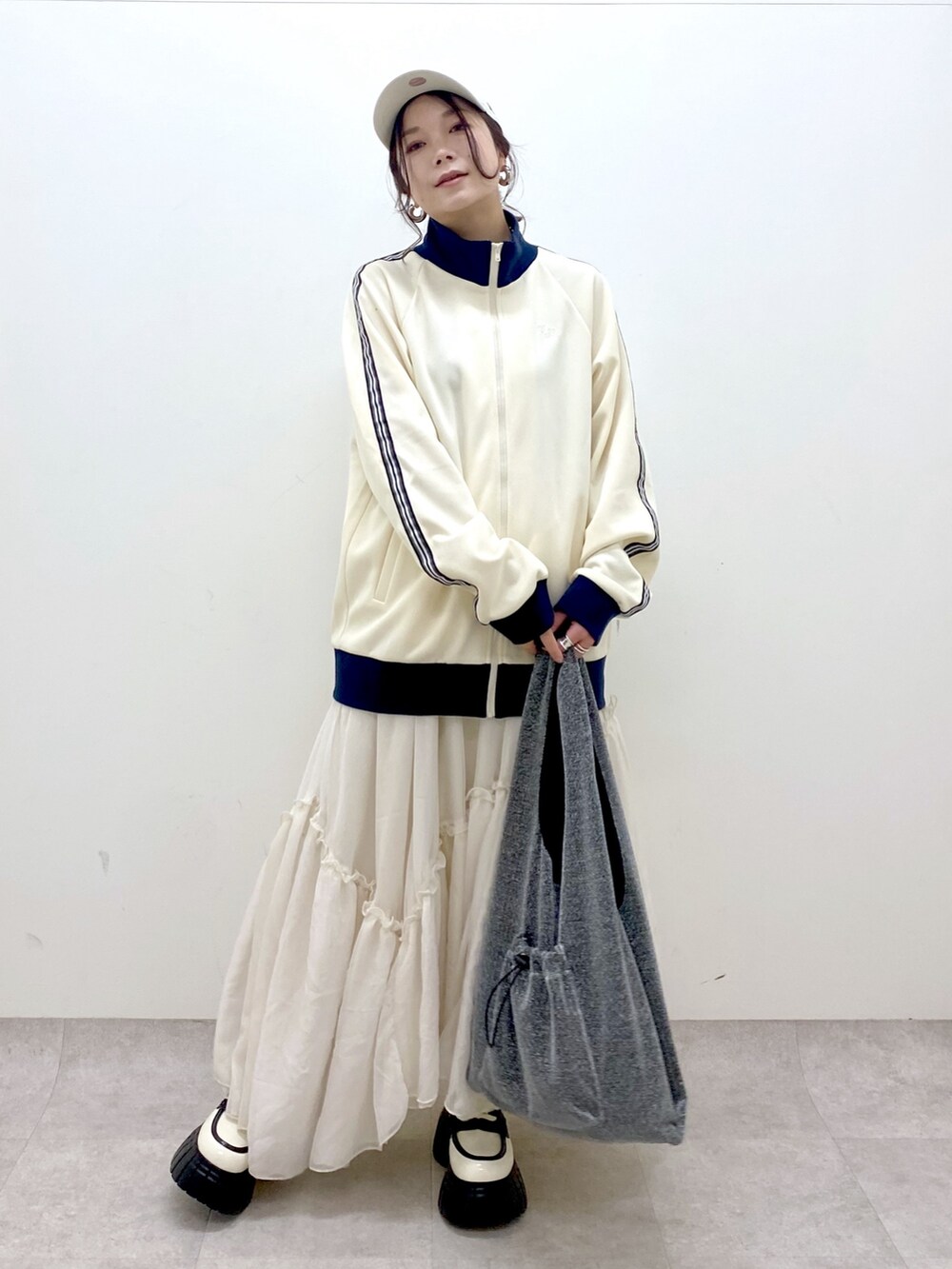 ホワイト系のセットアップ、ブラック系のトートバッグ、ホワイト系のスカートを着用したレディースの冬コーディネートの8枚目の写真