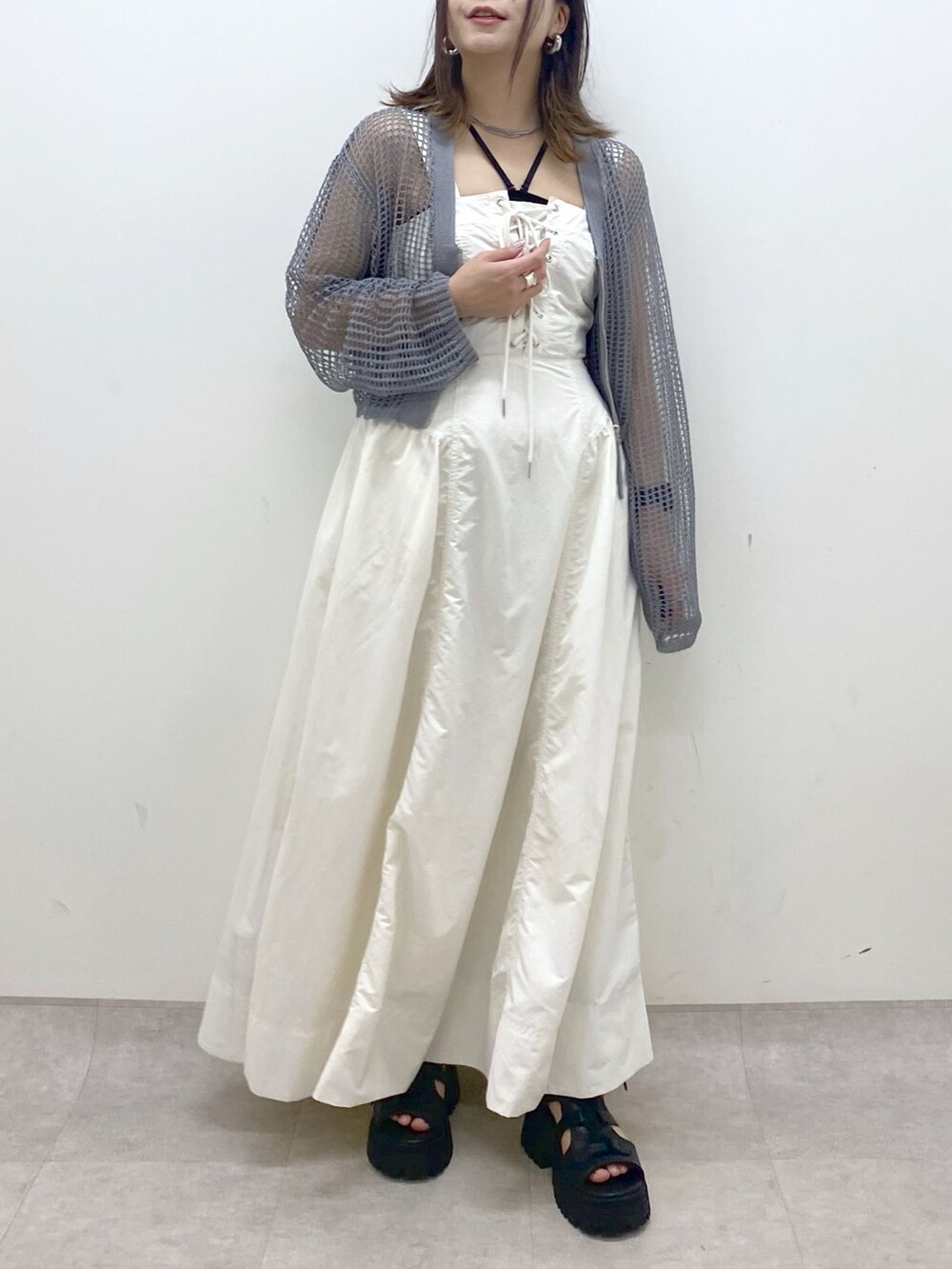 ホワイト系のワンピース、グレー系のカーディガン/ボレロ、ブラック系のサンダルを着用したレディースの春コーディネートの3枚目の写真
