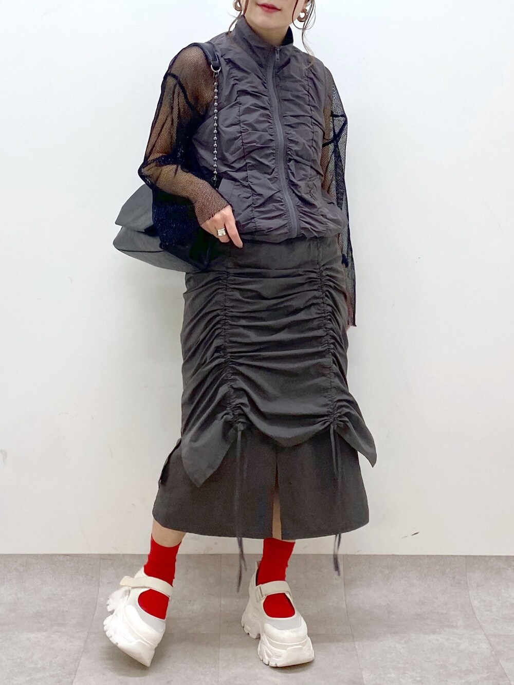 グレー系のスカート、ブラック系のショルダーバッグ、ブラック系のTシャツ/カットソーを着用したレディースの春コーディネートの3枚目の写真