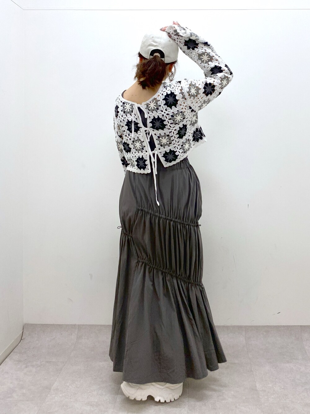 グレー系のスカート、ホワイト系のカーディガン/ボレロ、ブラック系のドラムバッグを着用したレディースの春コーディネートの6枚目の写真