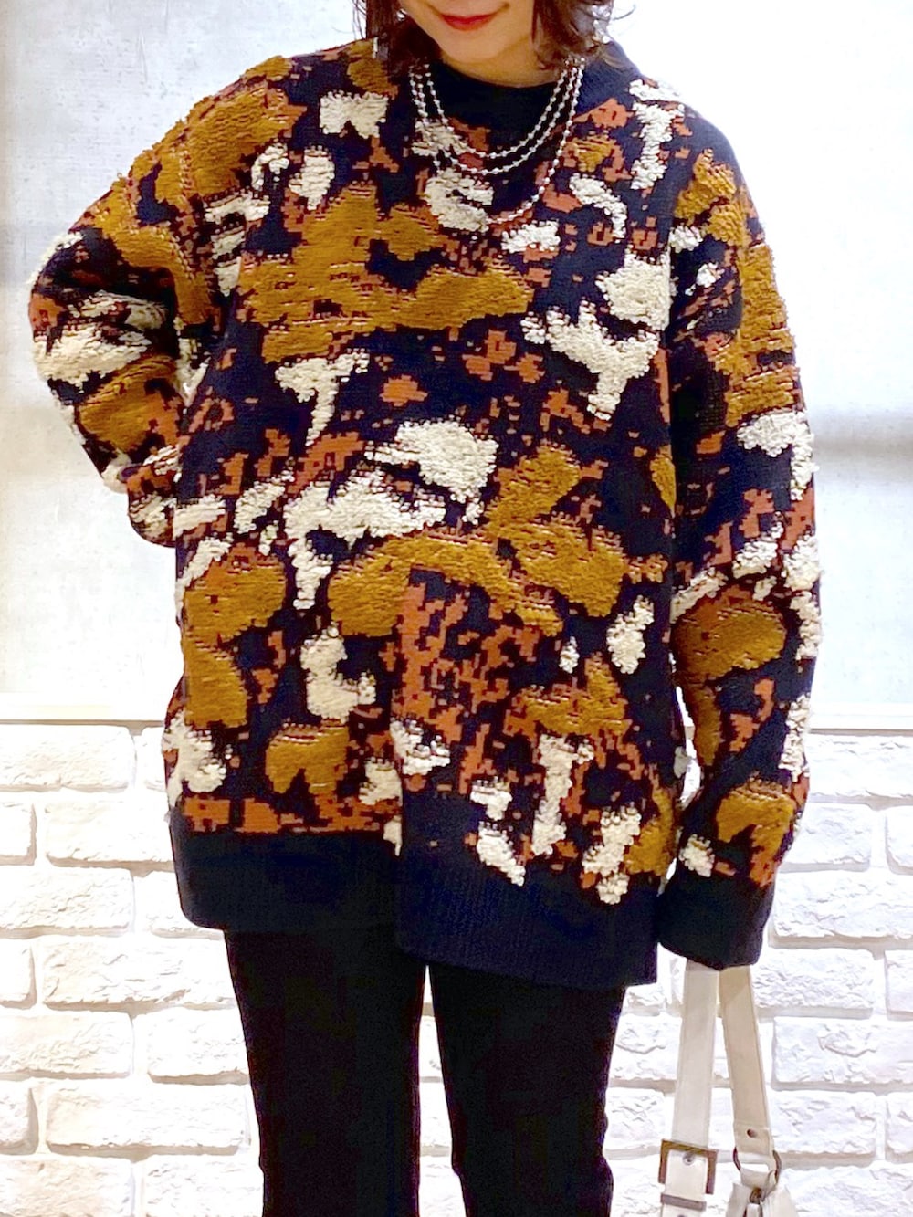 ブルー系のニット/セーター、ブルー系のデニムパンツ、ホワイト系のショルダーバッグを着用したレディースの冬コーディネートの2枚目の写真