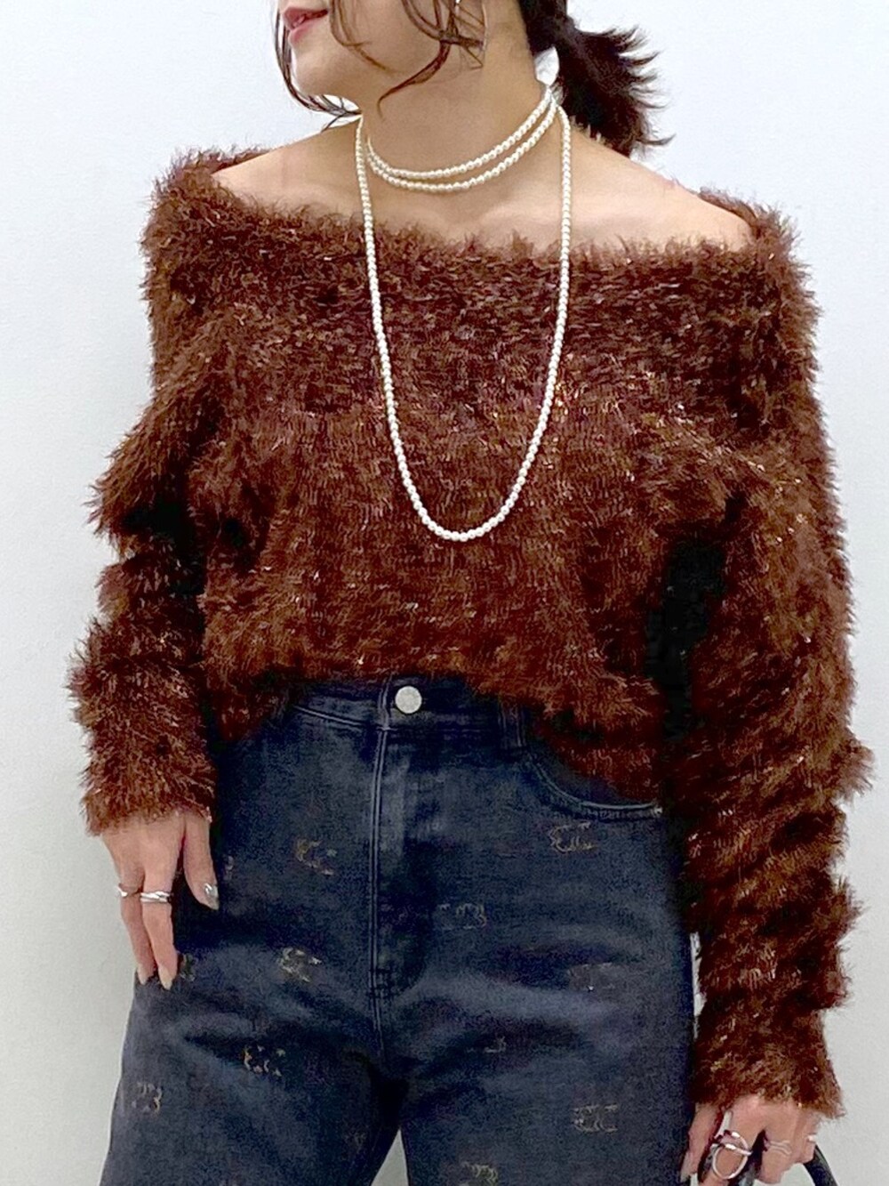 ブラウン系のニット/セーター、ブラック系のボストンバッグ、ホワイト系のスニーカーを着用したレディースの冬コーディネートの2枚目の写真