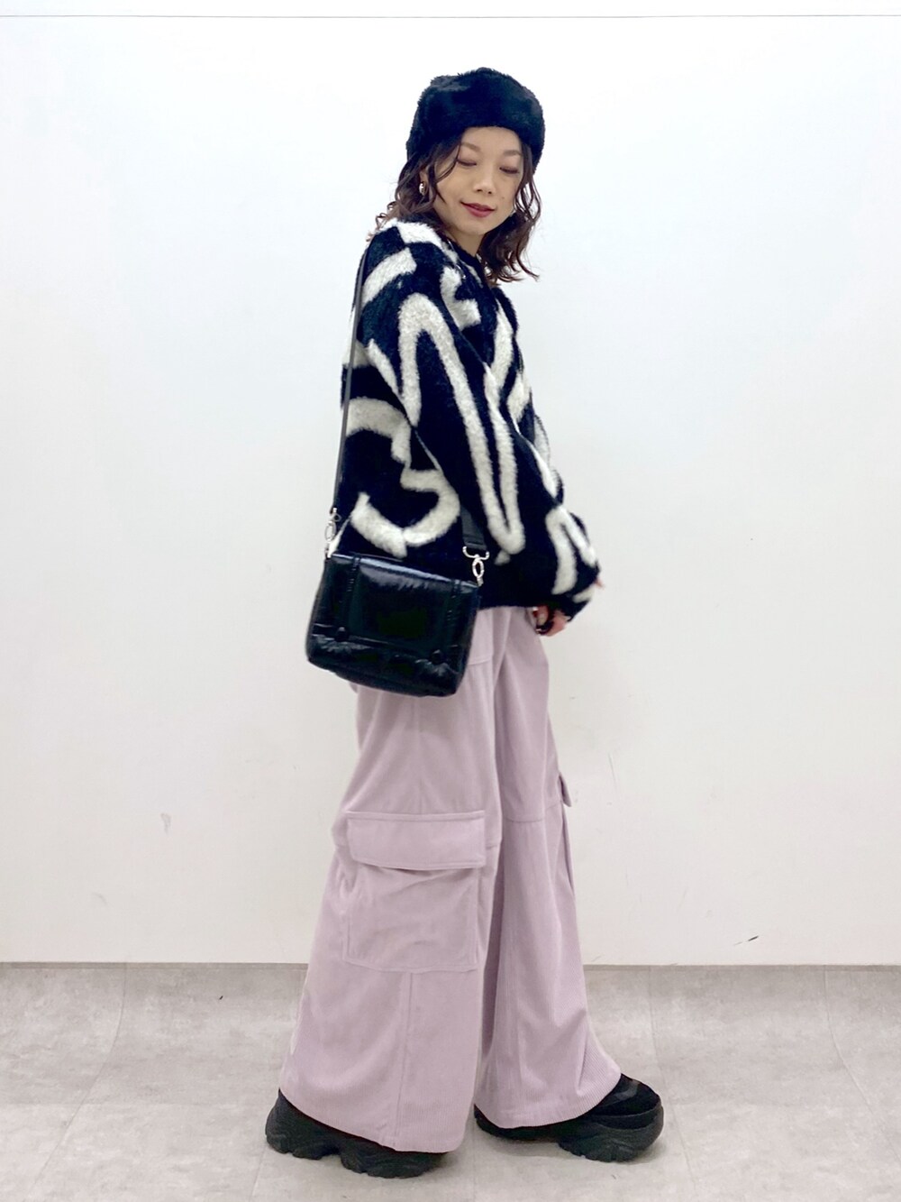 ピンク系のカーゴパンツ、ブラック系のニット/セーター、ブラック系のショルダーバッグを着用したレディースの冬コーディネートの3枚目の写真