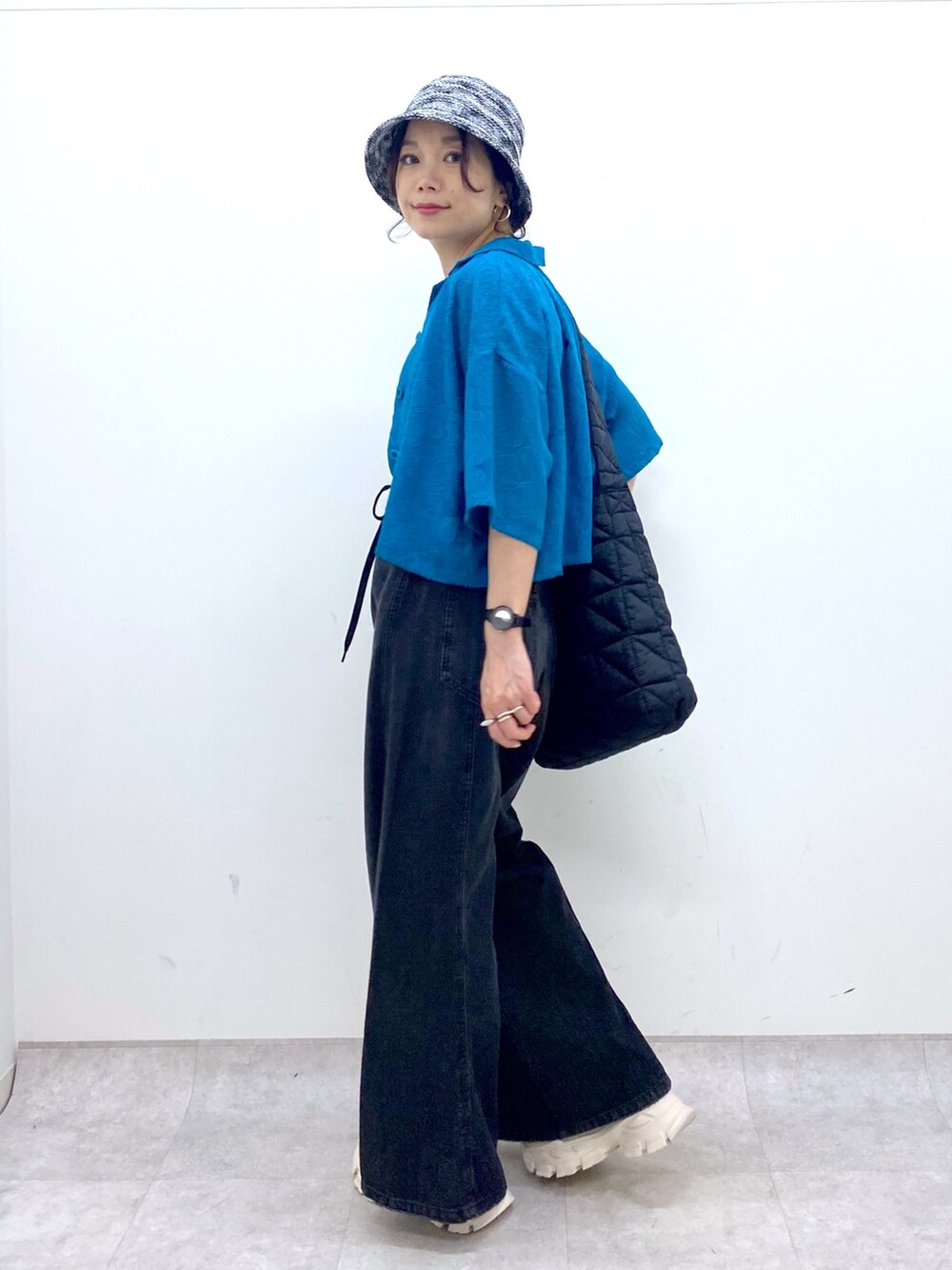 ブラック系のデニムパンツ、ブラック系のショルダーバッグ、ブルー系のタンクトップを着用したレディースの夏コーディネートの2枚目の写真