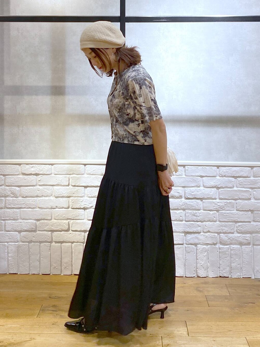 ブラック系のパンプス、ブラック系のスカート、ホワイト系のショルダーバッグを着用したレディースの夏コーディネートの7枚目の写真