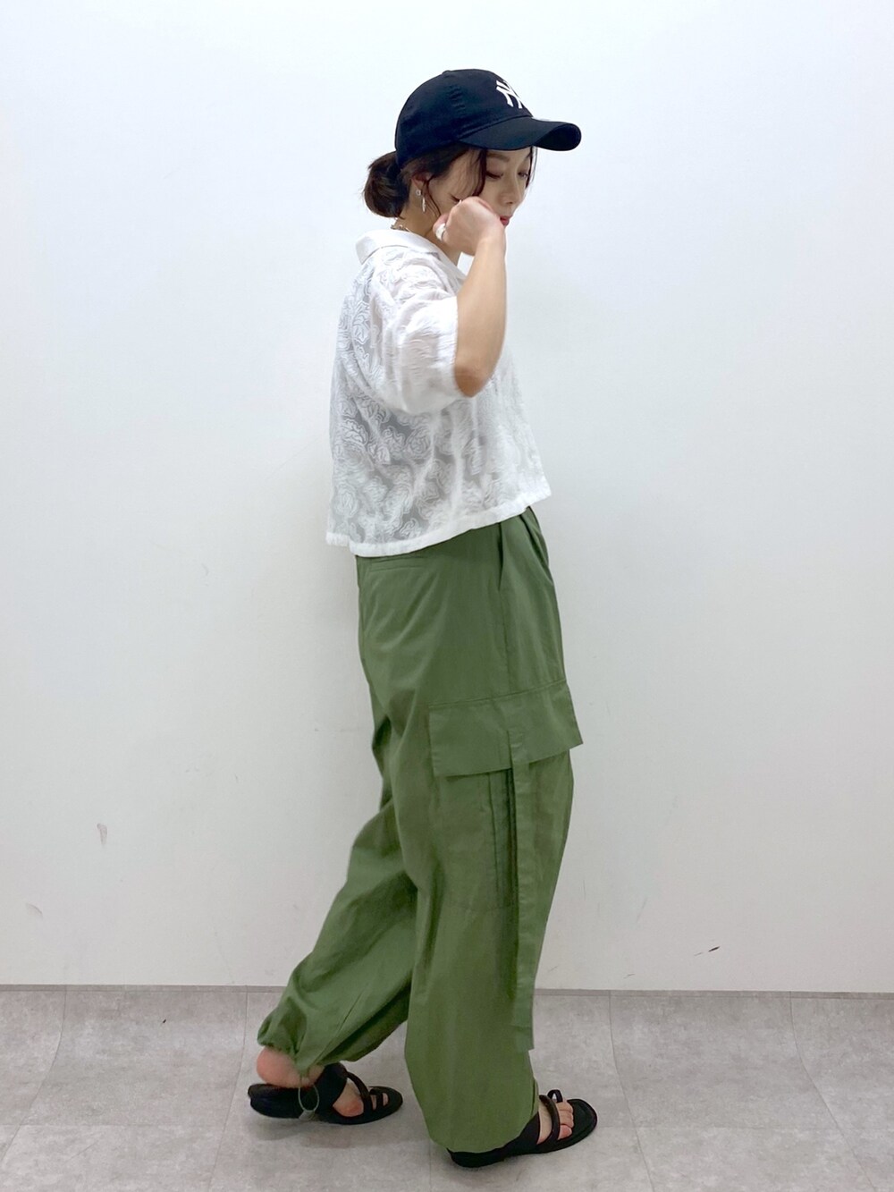 グリーン系のカーゴパンツ、ブラック系のサンダル、ブラック系のトップスを着用したレディースの夏コーディネートの2枚目の写真