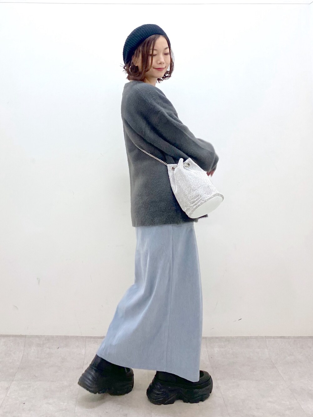 グレー系のニット/セーター、ブルー系のスカート、ブラック系のブーツを着用したレディースの秋コーディネートの7枚目の写真