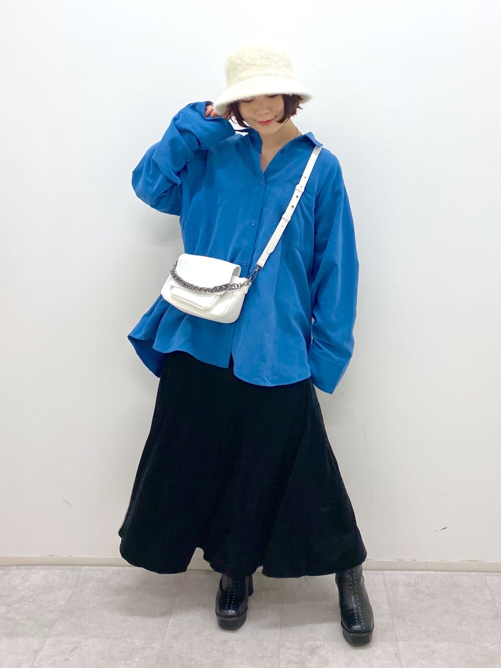 ブラック系のスカート、ホワイト系のバッグ、ブラック系のブーツを着用したレディースの秋コーディネートの5枚目の写真