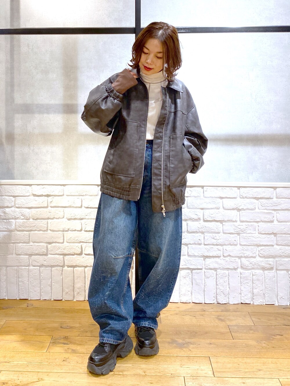 グレー系のブルゾン、ブルー系のデニムパンツ、ブラック系のブーツを着用したレディースの冬コーディネートの9枚目の写真