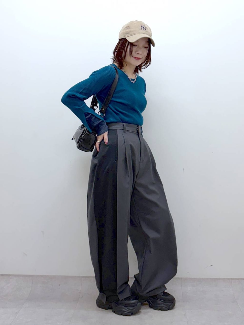 ブラック系のブーツ、グリーン系のニット/セーター、ブラック系のショルダーバッグを着用したレディースの冬コーディネートの5枚目の写真