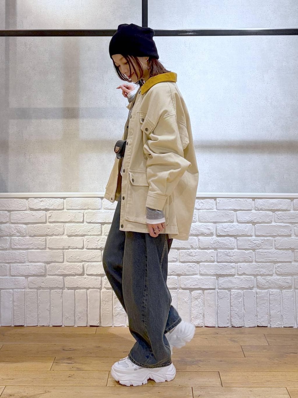 ホワイト系のスニーカー、ブラック系のボディバッグ/ウエストポーチ、ブルー系のデニムパンツを着用したレディースの冬コーディネートの7枚目の写真