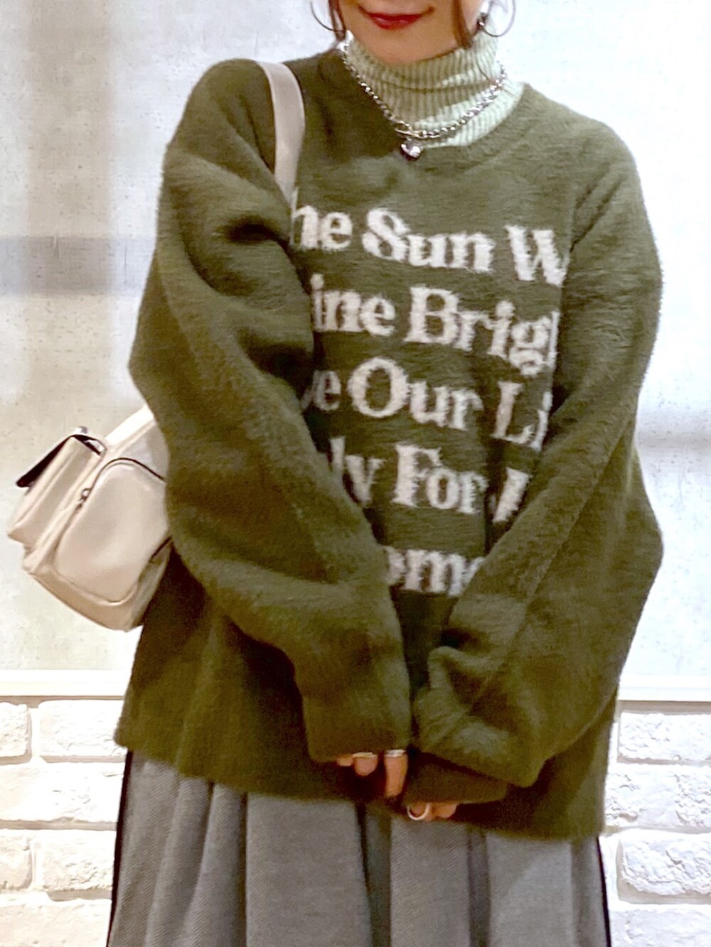 ブラック系のスラックス、グリーン系のTシャツ/カットソー、ブラック系のブーツを着用したレディースの冬コーディネートの2枚目の写真
