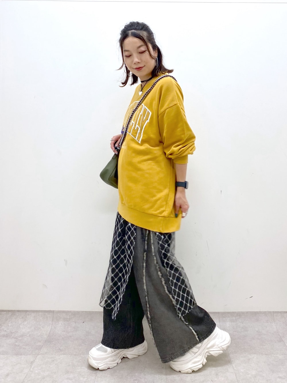 イエロー系のスウェット、ブラック系のデニムパンツ、ホワイト系のスニーカーを着用したレディースの夏コーディネートの4枚目の写真