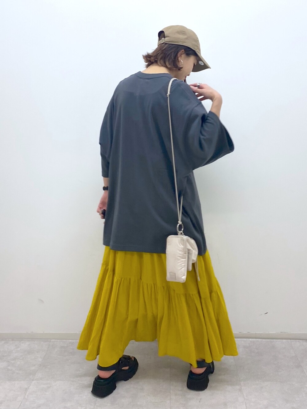 グレー系のTシャツ/カットソー、イエロー系のスカート、ブラック系のサンダルを着用したレディースの夏コーディネートの3枚目の写真