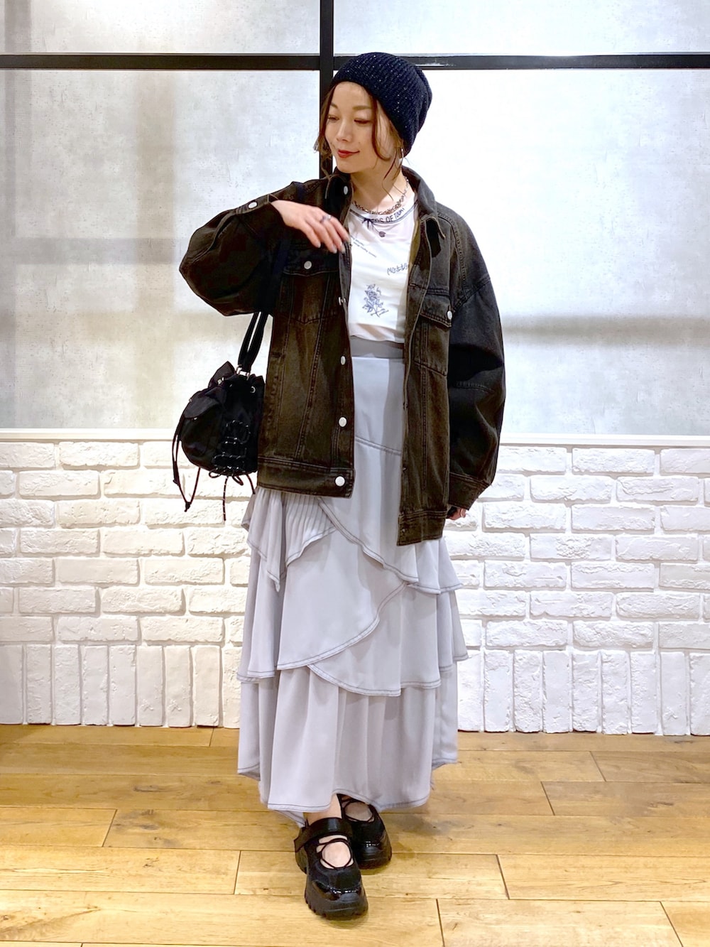 ブラック系のデニムジャケット、グレー系のスカート、ブラック系のスニーカーを着用したレディースの春コーディネートの8枚目の写真