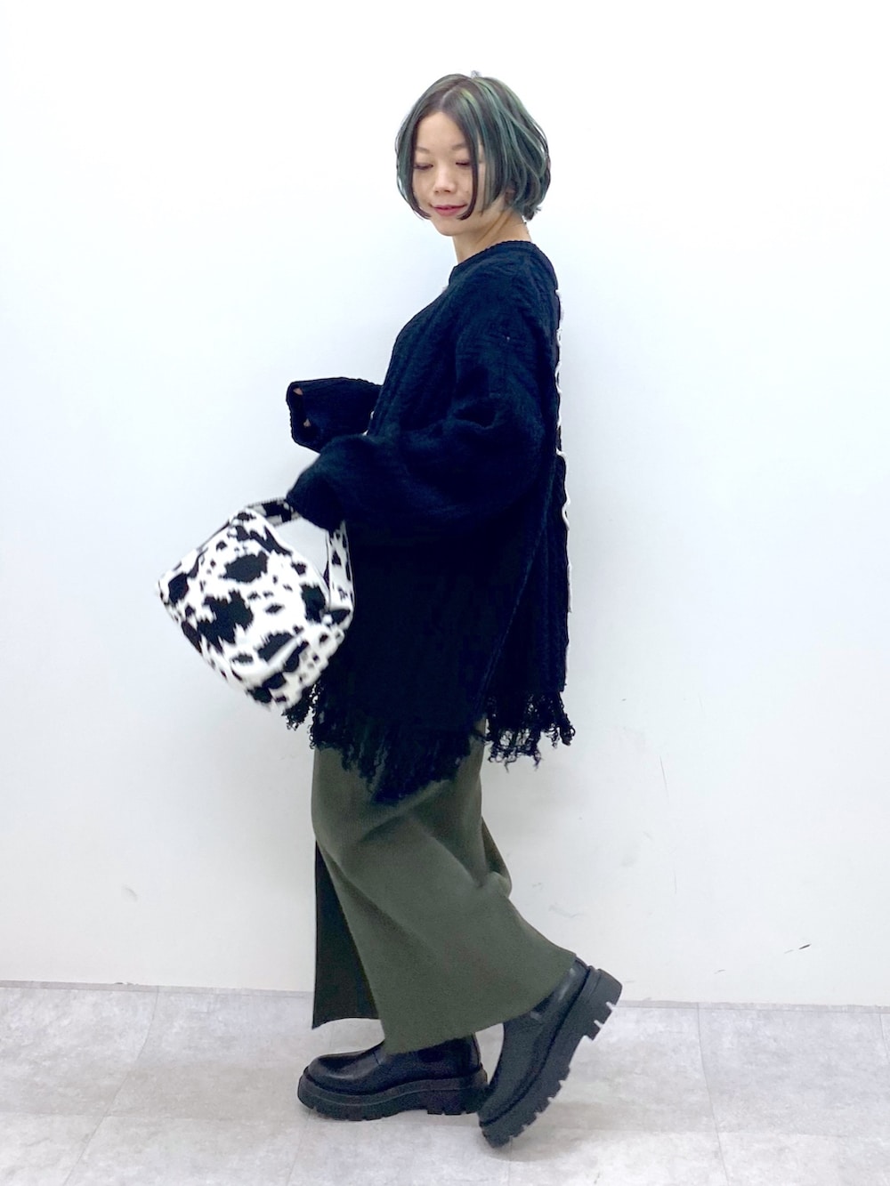 ブラック系のトップス、グリーン系のスカート、ブラック系のバッグを着用したレディースの冬コーディネートの3枚目の写真