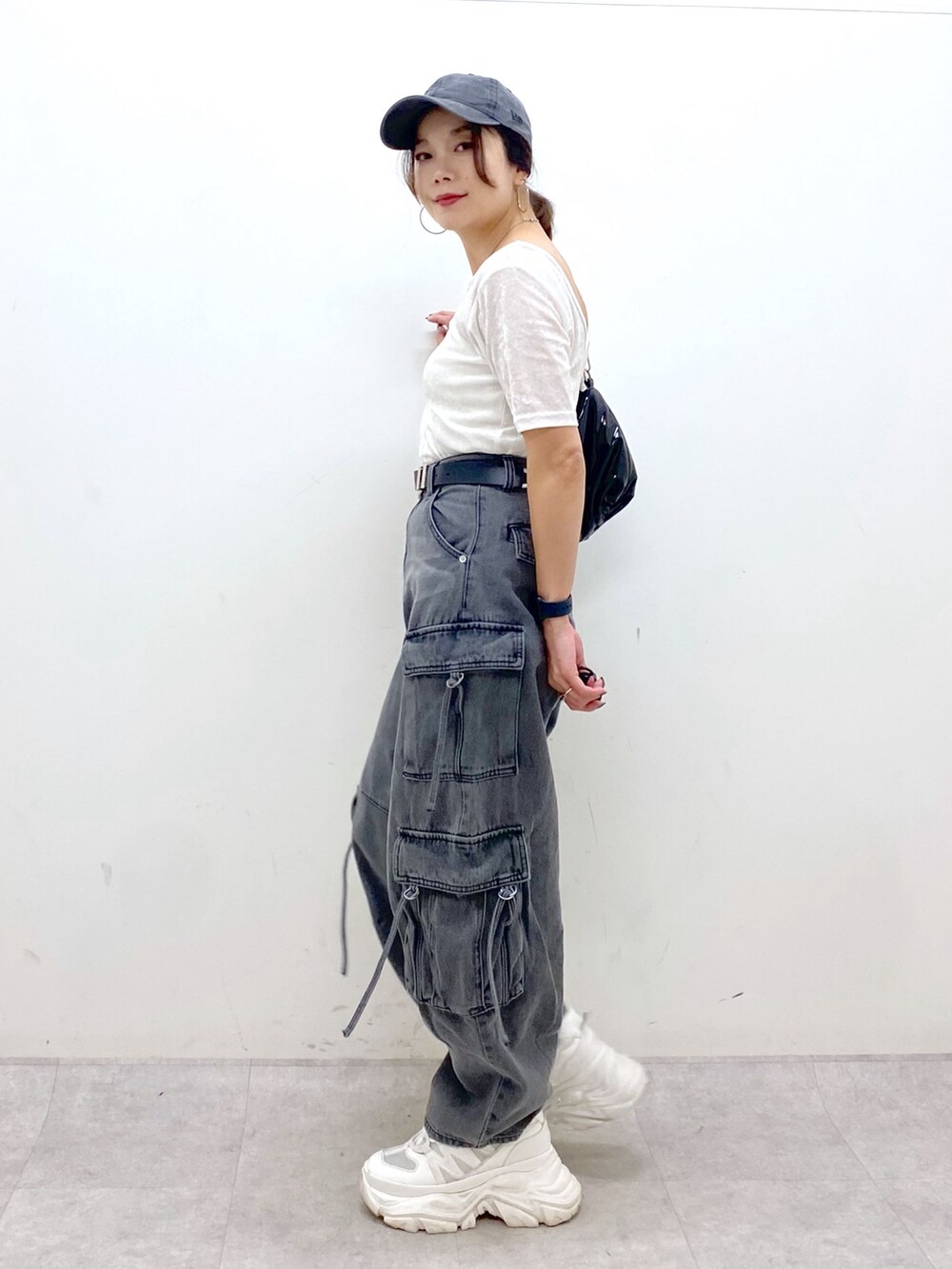 ブラック系のデニムパンツ、ホワイト系のスニーカー、ブラック系のショルダーバッグを着用したレディースの夏コーディネートの8枚目の写真