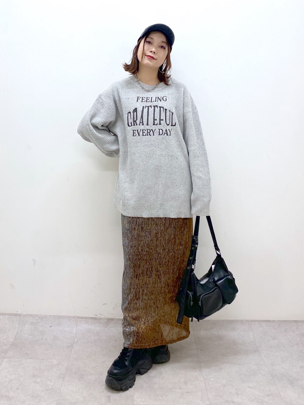 グレー系のニット/セーター、ゴールド系のスカート、ブラック系のショルダーバッグを着用したレディースの冬コーディネートの9枚目の写真