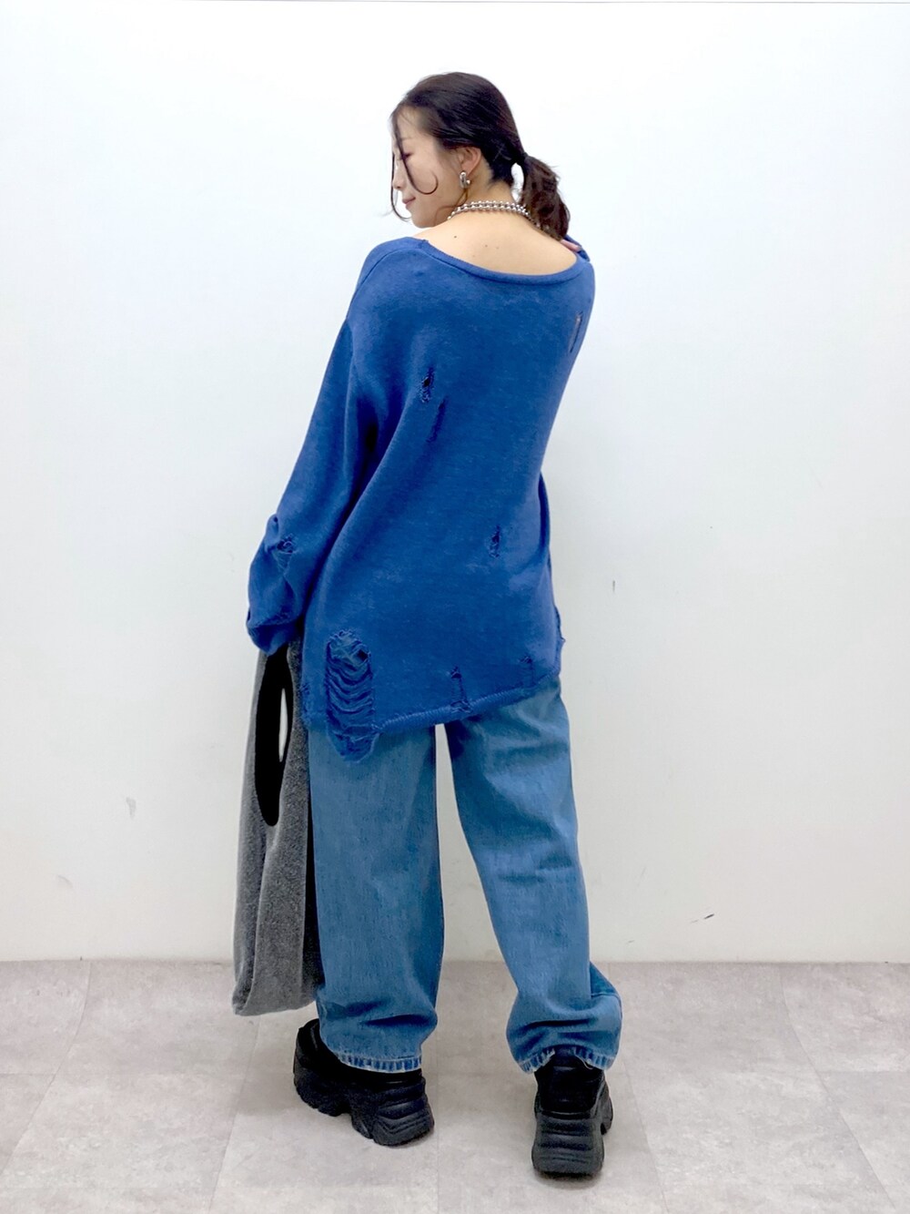 ブルー系のニット/セーター、ブルー系のデニムパンツ、ブラック系のトートバッグを着用したレディースの冬コーディネートの7枚目の写真
