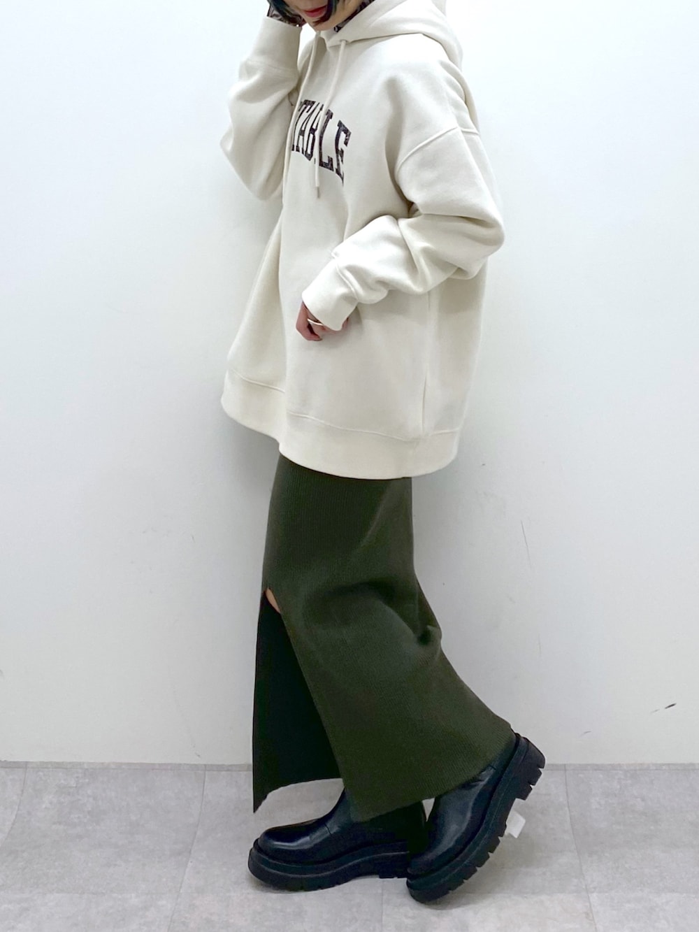 ホワイト系のパーカー、ブラック系のトップス、ブラック系のシューズを着用したレディースの秋コーディネートの4枚目の写真