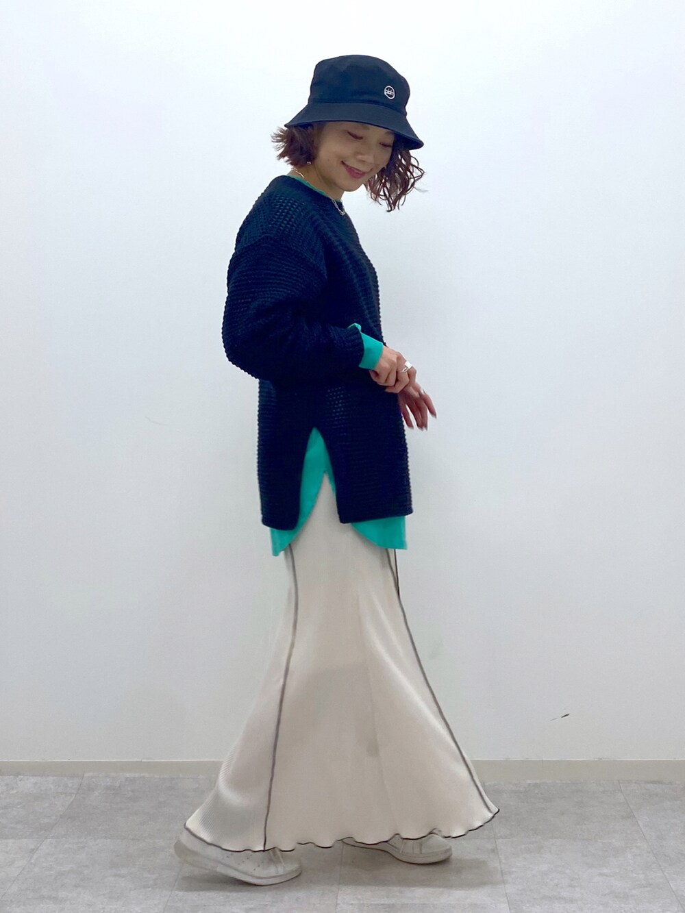 ブラック系のニット/セーター、グリーン系のTシャツ/カットソー、ホワイト系のスカートを着用したレディースの春コーディネートの3枚目の写真