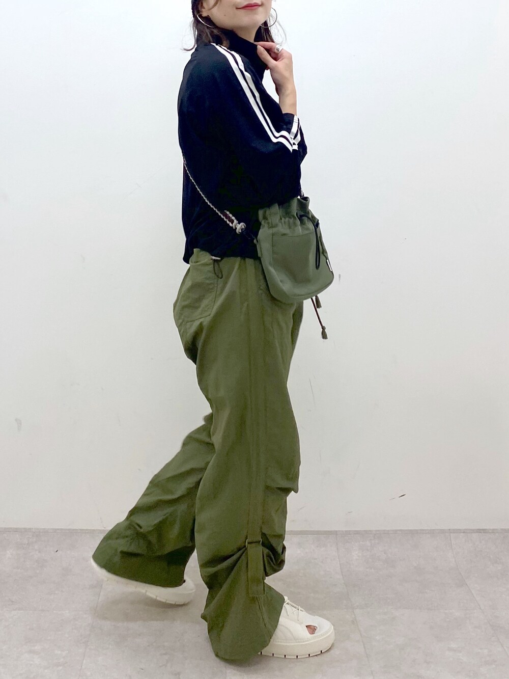 グリーン系のカーゴパンツ、ホワイト系のスニーカー、グリーン系のショルダーバッグを着用したレディースの夏コーディネートの3枚目の写真