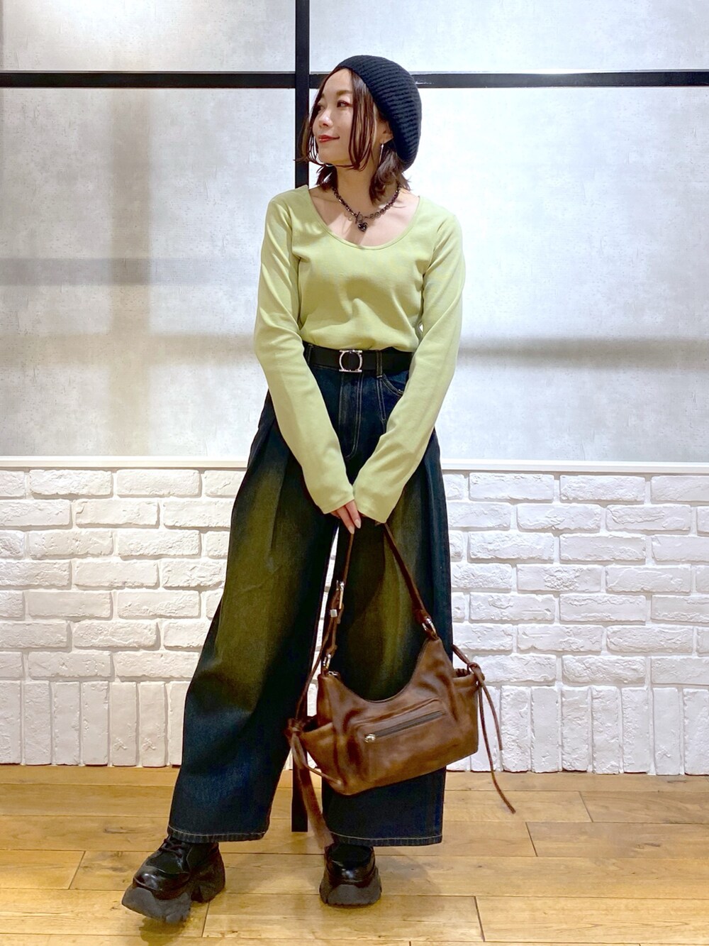 イエロー系のTシャツ/カットソー、ブラウン系のショルダーバッグ、ブルー系のデニムパンツを着用したレディースの冬コーディネートの3枚目の写真