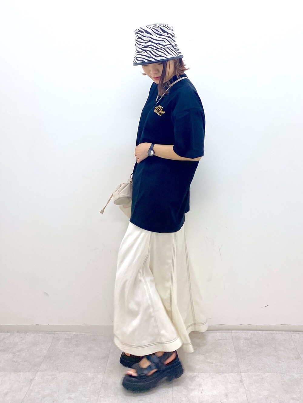 ベージュ系のショルダーバッグ、ブラック系のサンダル、ブラック系のTシャツ/カットソーを着用したレディースの夏コーディネートの3枚目の写真