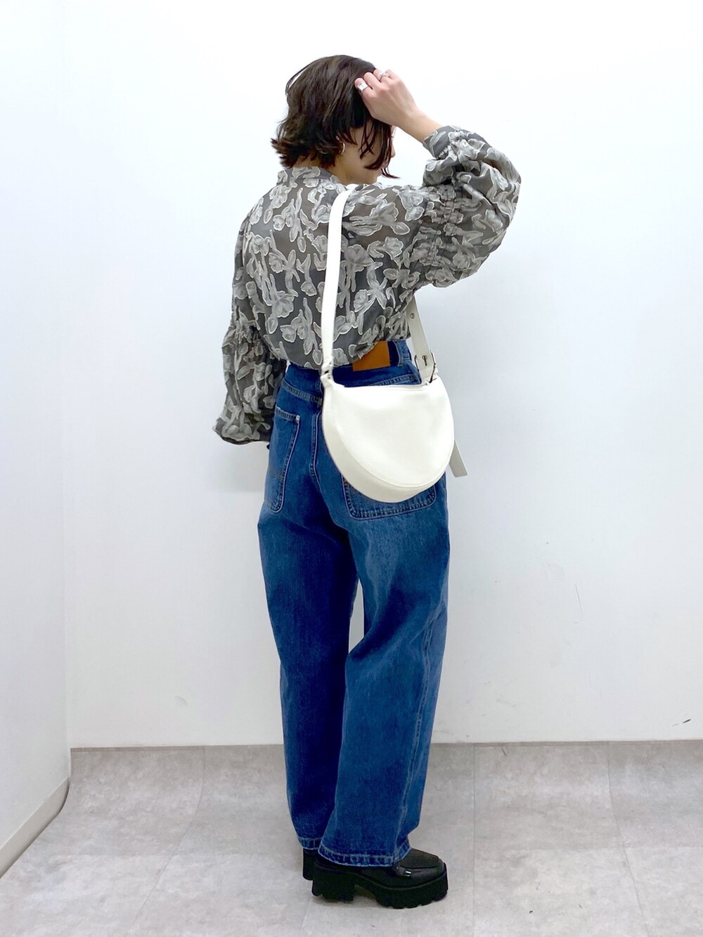 ブルー系のパンツ、グレー系のトップス、ホワイト系のショルダーバッグを着用したレディースの春コーディネートの2枚目の写真