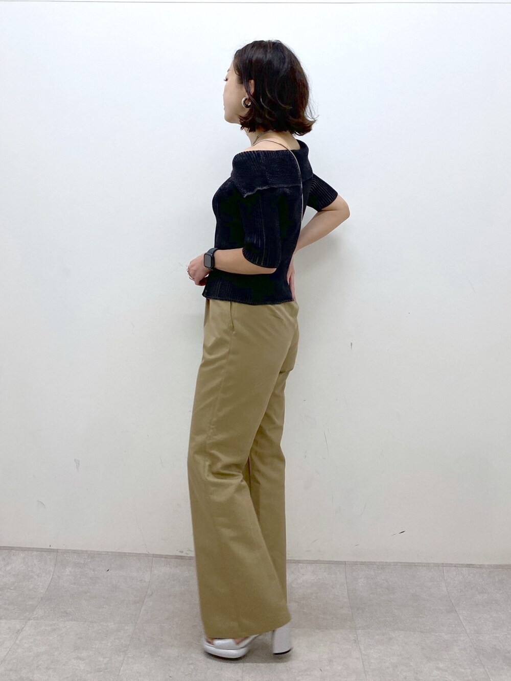 ブラック系のニット/セーター、ベージュ系のチノパンツ、ブラック系のショルダーバッグを着用したレディースの春コーディネートの5枚目の写真