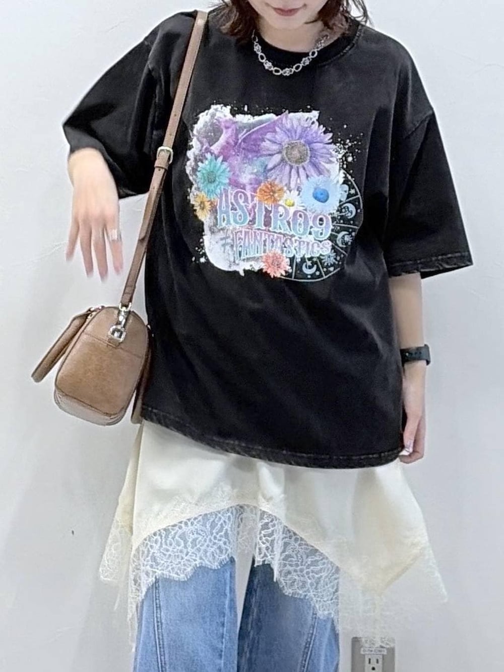 ブルー系のデニムパンツ、ブラウン系のボストンバッグ、ホワイト系のチュニックを着用したレディースの春コーディネートの2枚目の写真